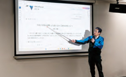スクリーンに資料を表示して説明する担当者